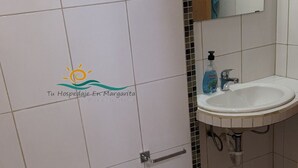 A bathroom with a white toilet, a sink, and a mirror.