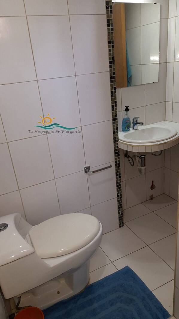 A bathroom with a white toilet, a sink, and a mirror.