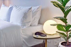 A neatly made bed with white bedding, a bedside table with a lamp, a plant, and a pair of sunglasses. - w Cozy Loft in the Heart of Bogot (Bogotá)