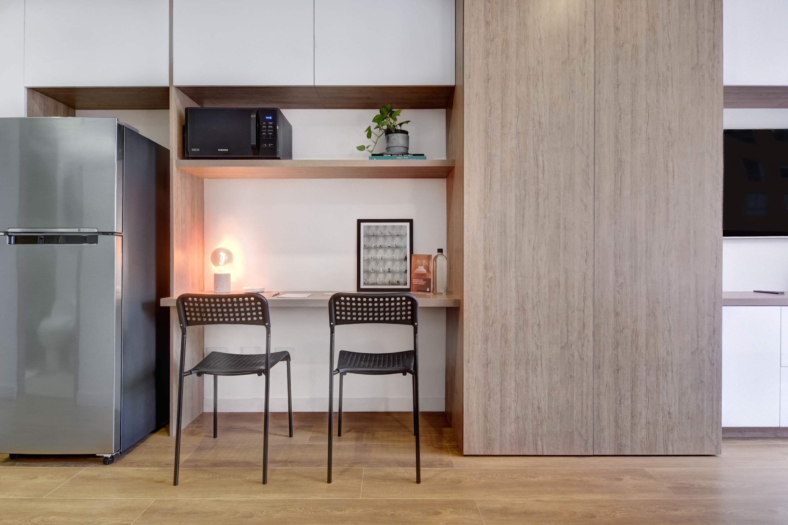 Eine moderne Küche mit integriertem Mikrowellenherd, einem Kühlschrank und zwei Stühlen.