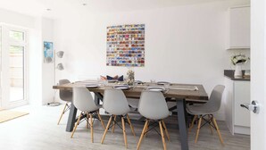 A dining area with a long table, six chairs, and a wall art piece above the table. - Modern Family Retreat Nr Beaches and Marina (Chichester)