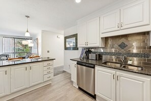 A modern kitchen with white cabinets, stainless steel appliances, and a granite countertop.