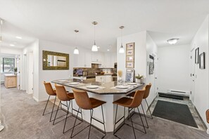 A modern kitchen with a central island, bar stools, pendant lighting, and a backsplash with a decorative tile pattern. - Powder Pad Park Ave | Ski, Après & Downtown Fun (Park City)