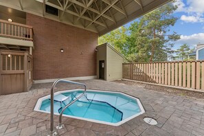 A covered outdoor swimming pool with a metal ladder, surrounded by a brick wall and wooden deck. - Powder Pad Park Ave | Ski, Après & Downtown Fun (Park City)