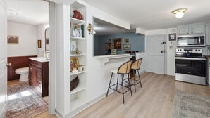 Una cocina equipada con microondas, horno y taburetes de bar.