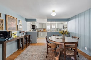A dining area with a round table, chairs, a rug, and a kitchen in the background. - Farmhouse Retreat - Near Pigeon Forge & Dollywood (Sevierville)