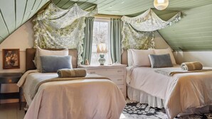 Una habitación con dos camas, una mesita de noche, una lámpara y una ventana con cortinas.