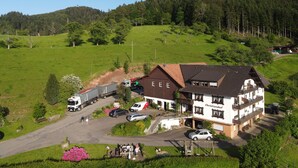 A building with a sloped roof, a parking area, and a green field in the background. - Christianshof - Holiday Apartment '3' with Mountain View, Shared Garden and Wi-Fi (Oppenau)