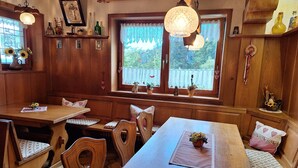 A cozy kitchen with wooden cabinets, a dining table, and a window with decorative items. - Christianshof - Holiday Apartment '3' with Mountain View, Shared Garden and Wi-Fi (Oppenau)