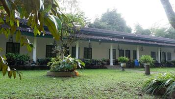 A building with a tiled roof and columns, surrounded by a well-maintained lawn and potted plants.