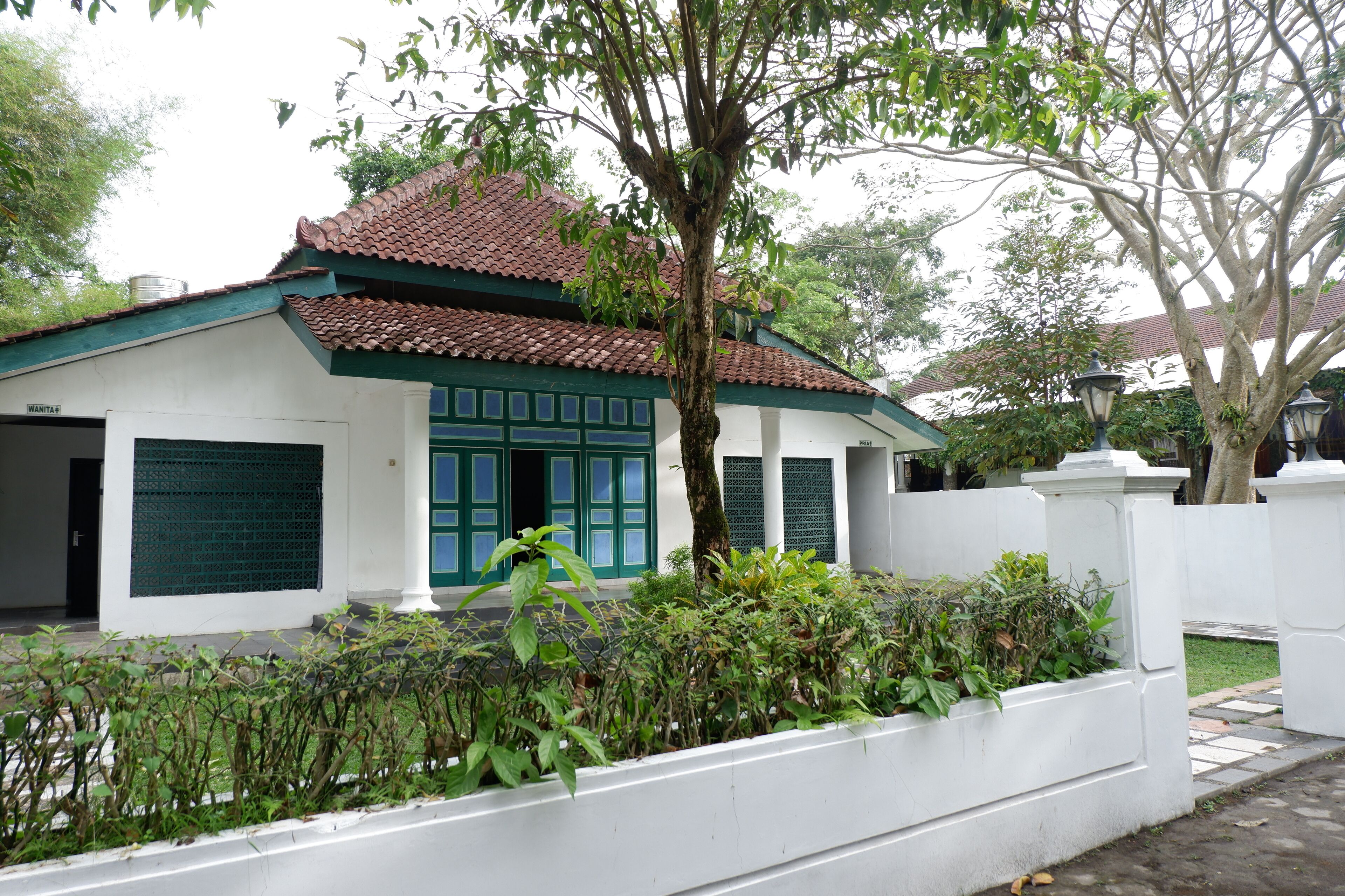 A traditional house with a tiled roof, green shutters, and a white exterior.