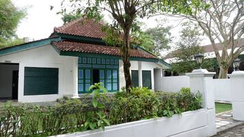 A traditional house with a tiled roof, green shutters, and a white exterior.