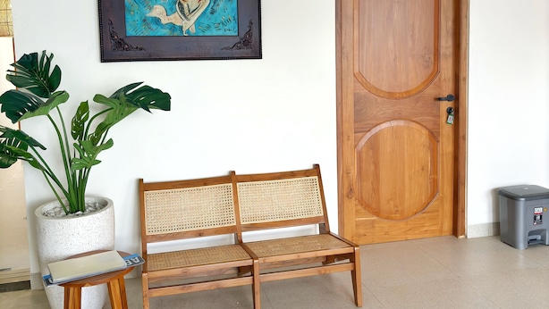A wooden bench, a potted plant, a framed artwork, and a wooden door. - NUMAR VILLAS - Bohemian with privatepool (Depok)