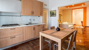A modern kitchen with wooden cabinets, a gas stove, and a dining area with a table and chairs. - Roomy Family Apartment by Wonderful Italy (Bari)