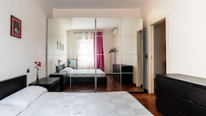 A modern bedroom with a large bed, a dresser, a mirror, and a wardrobe. - Roomy Family Apartment by Wonderful Italy (Bari)