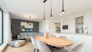 Una cocina moderna con armarios blancos, horno integrado y pileta de acero inoxidable.