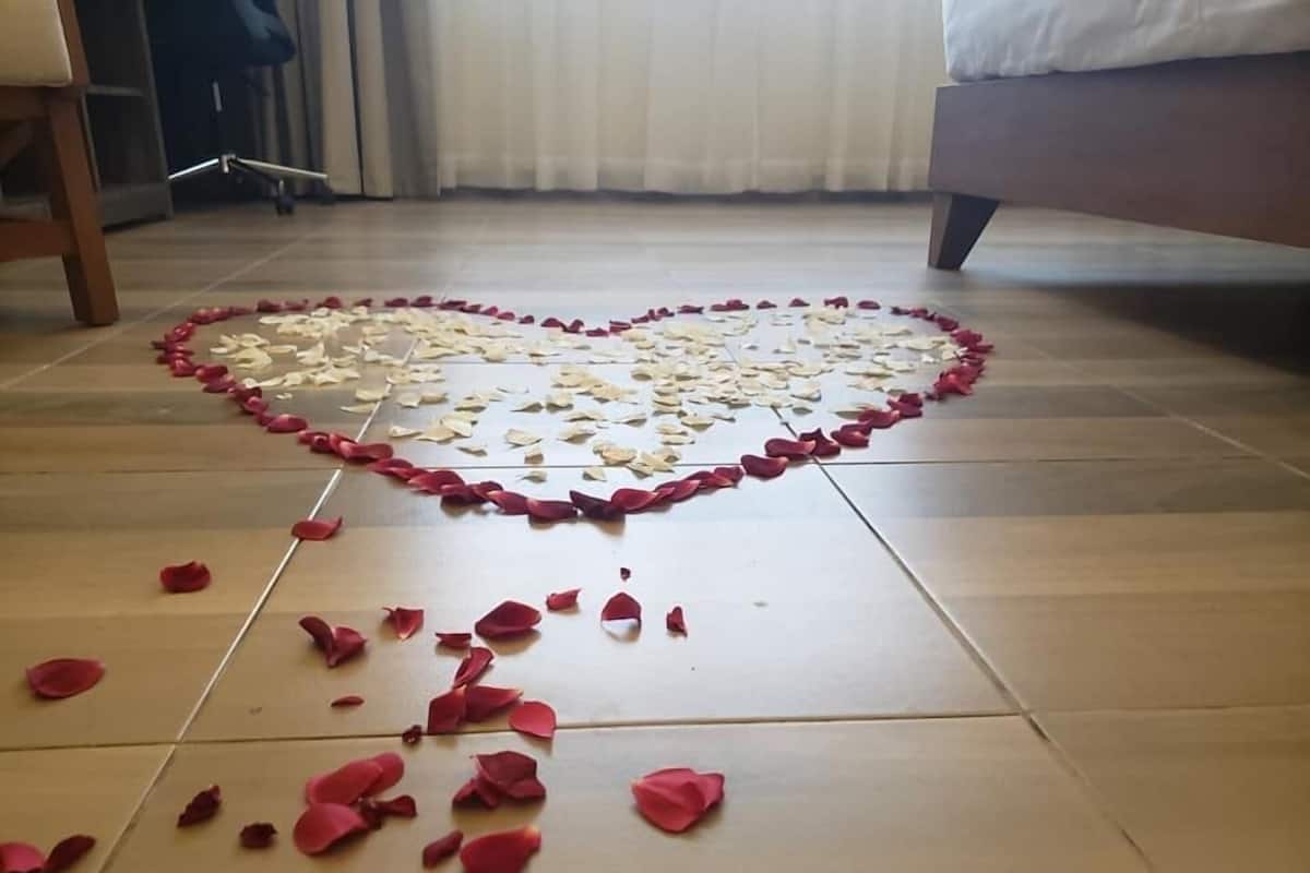 Un arreglo con forma de corazón de pétalos de rosa sobre un suelo de baldosas.