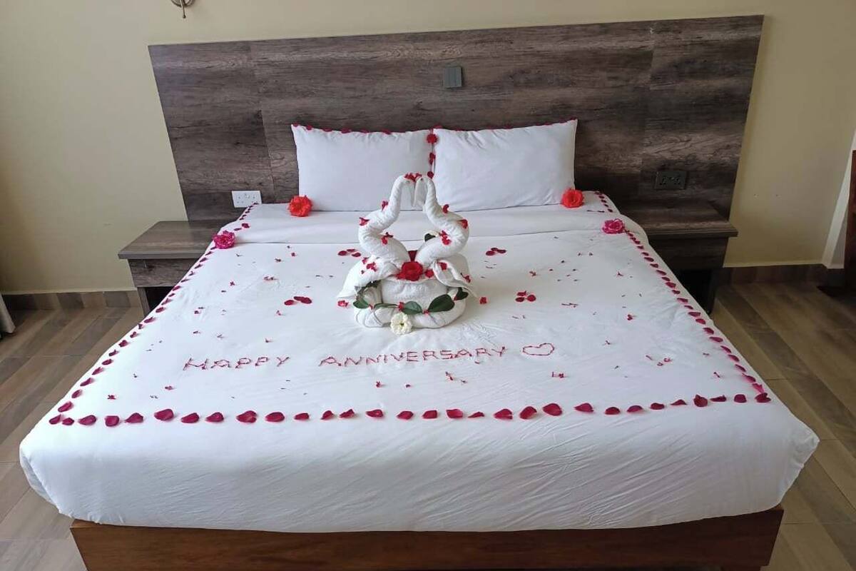 Una cama con una colcha blanca, una decoración de cisne y la inscripción “Happy Anniversary”.