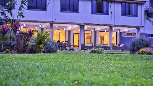 Un hôtel doté d’un espace extérieur couvert aménagé en coin salon, de nombreuses fenêtres et d’un jardin bien entretenu.
