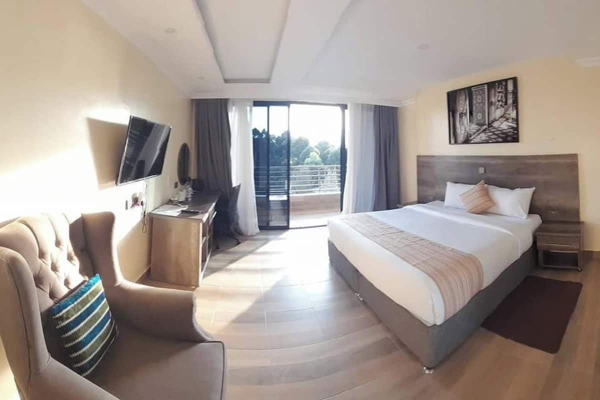 Una habitación de hotel con cama, sofá, televisión y balcón.
