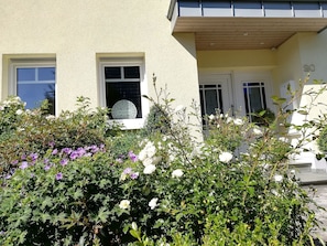A building with a beige facade, two windows with white frames, and a door with a white frame.