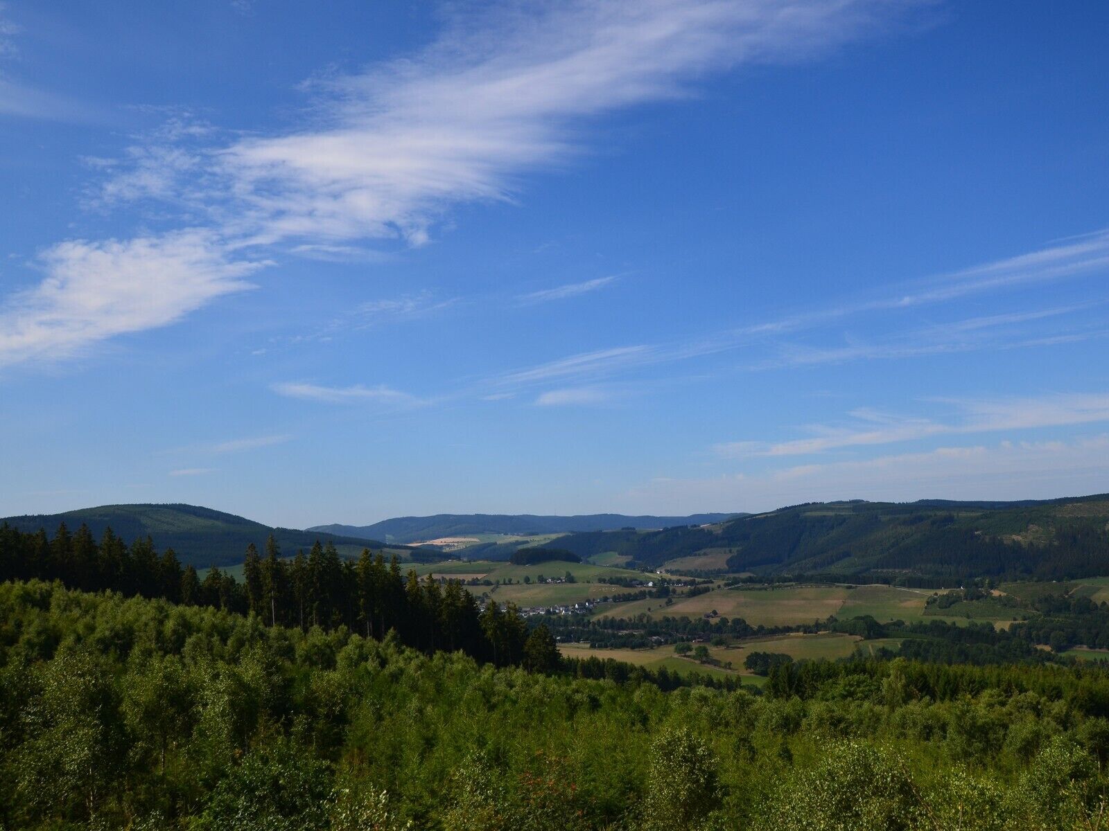 Ein weiter Panoramablick auf eine hügelige Landschaft unter blauem Himmel.