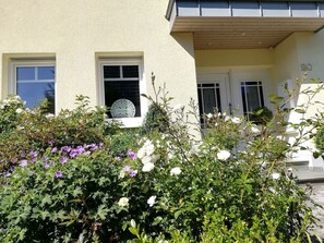 A building with a beige facade, two windows with white frames, and a door with a white frame.