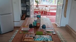 A dining area with a long wooden table set for a meal, a refrigerator, and a view of the outdoors. - Il poggio (Agrigento)