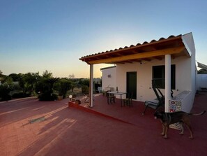 A patio area with a covered seating area, a table, and a dog. - Il poggio (Agrigento)