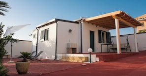 A small, single-story building with a covered patio area, a stone fireplace, and a seating arrangement. - Il poggio (Agrigento)