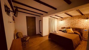 A bedroom with a wooden floor, a bed with a brown bedspread, a chair, and a wall with a floral pattern. - Il poggio (Agrigento)