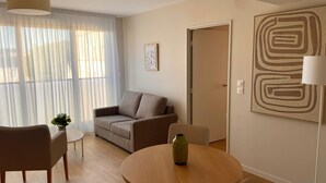 A modern living room with a sofa, a round table, and a lamp. - Zenao Appart'hôtels Mâcon (Mâcon)