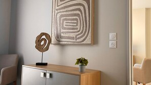 A modern living room with a wooden cabinet, a decorative metal piece, and a potted plant. - Zenao Appart'hôtels Mâcon (Mâcon)