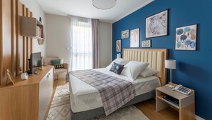A modern bedroom with a bed, bedside table, lamp, and artwork on the wall. - Zenao Appart'hôtels Mâcon (Mâcon)