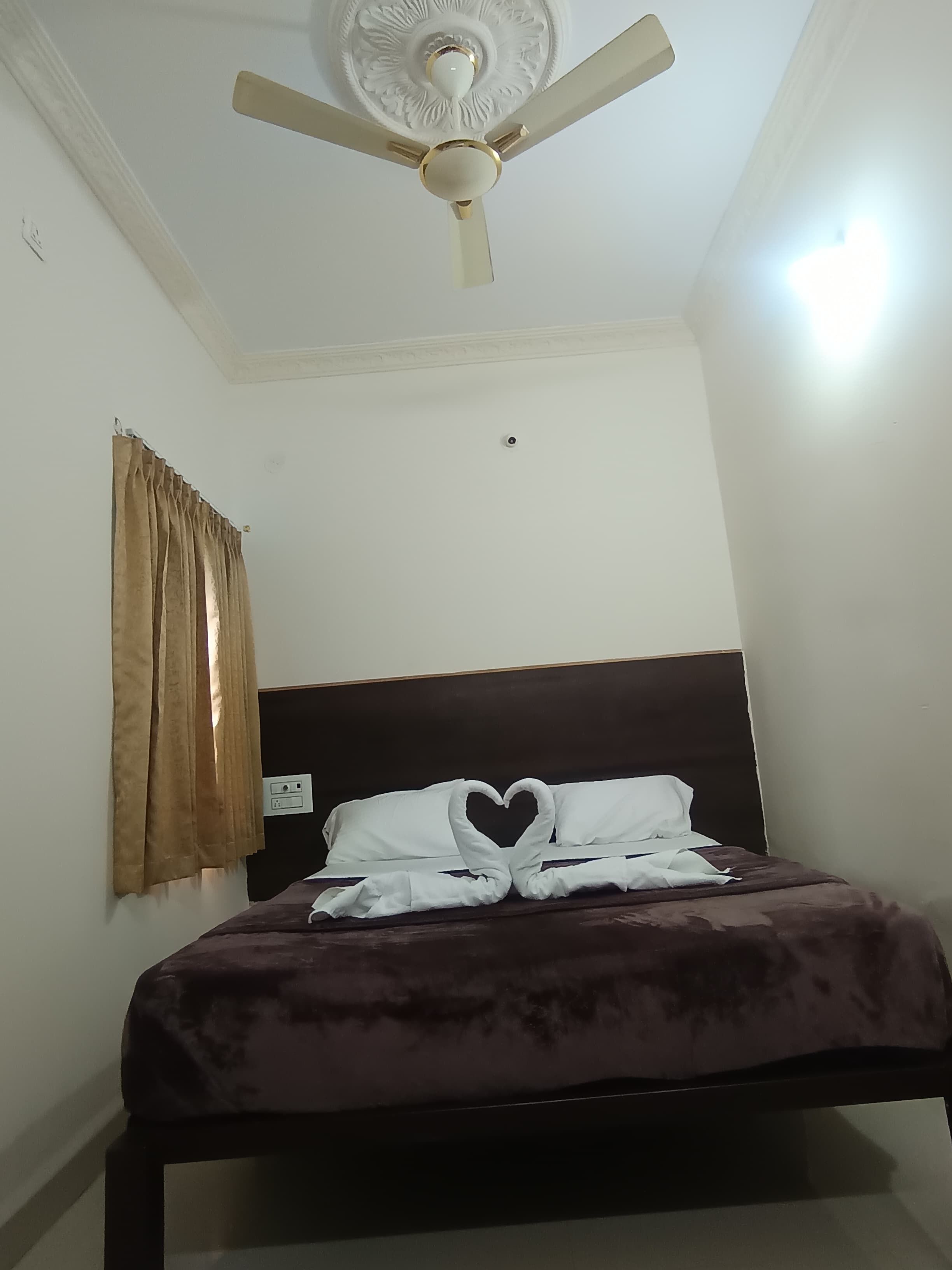 A bedroom with a bed, a ceiling fan, and a window with curtains.