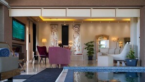 Um hall amplo com piscina, áreas de estar e uma televisão.