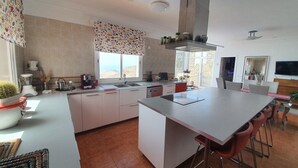 Una cocina moderna con una isla central, armarios blancos y un amplio ventanal con vistas al paisaje.