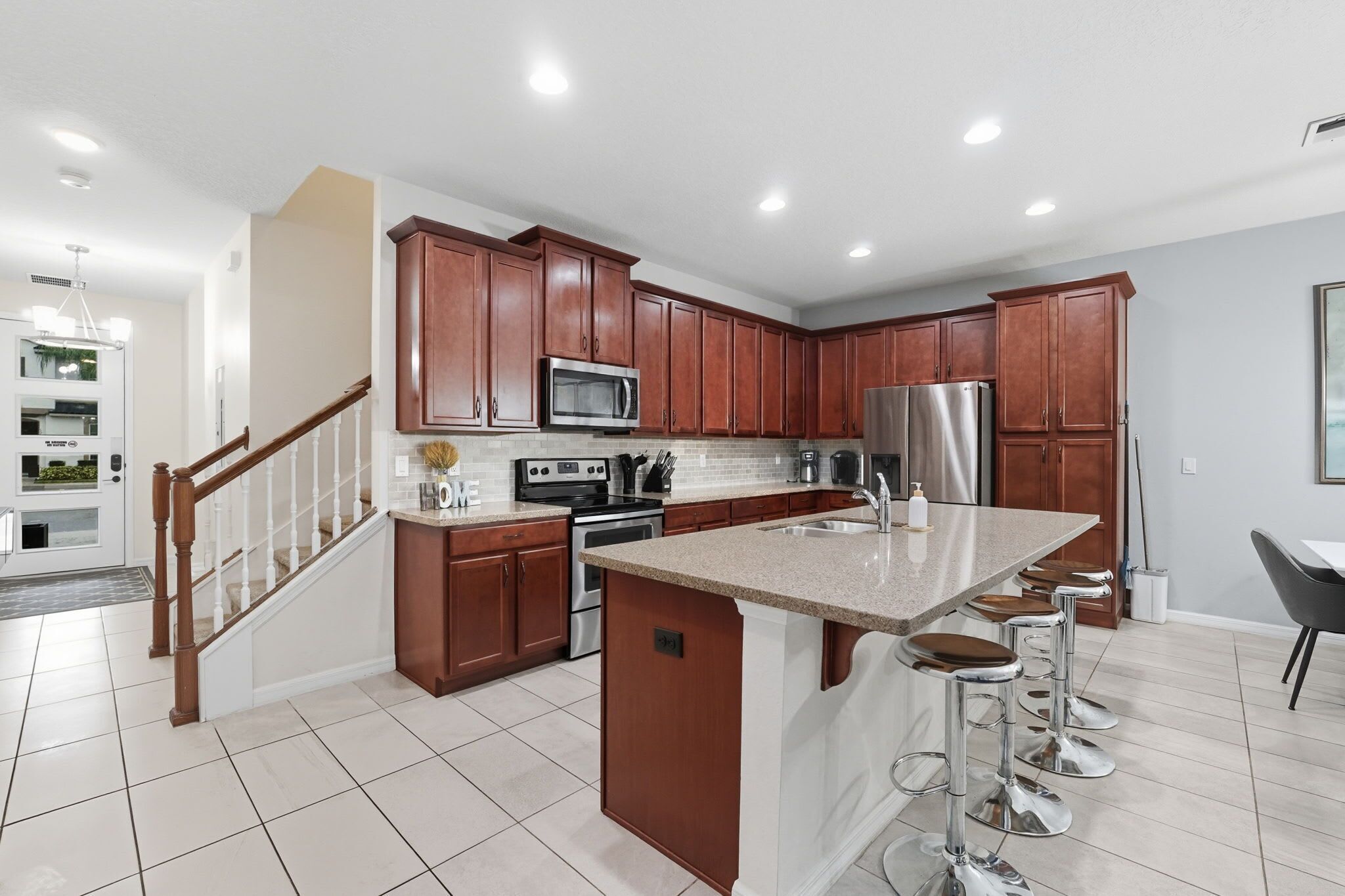 A modern kitchen with wooden cabinets, stainless steel appliances, and a central island with bar stools.
