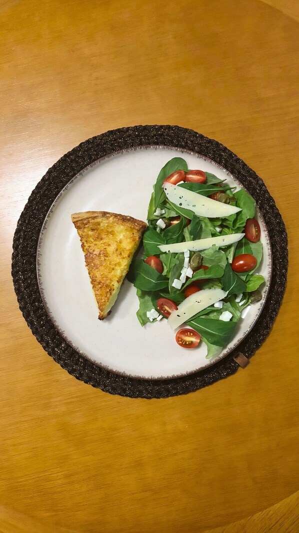 A plate with a slice of pizza and a salad on a round table. - Sítio Nova União - Pousada (Itamonte)