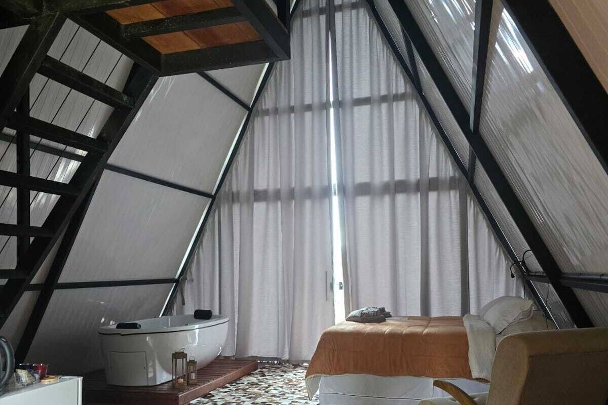 A cozy attic bedroom with a sloped ceiling, a bed, a chair, a small table, and a heater.