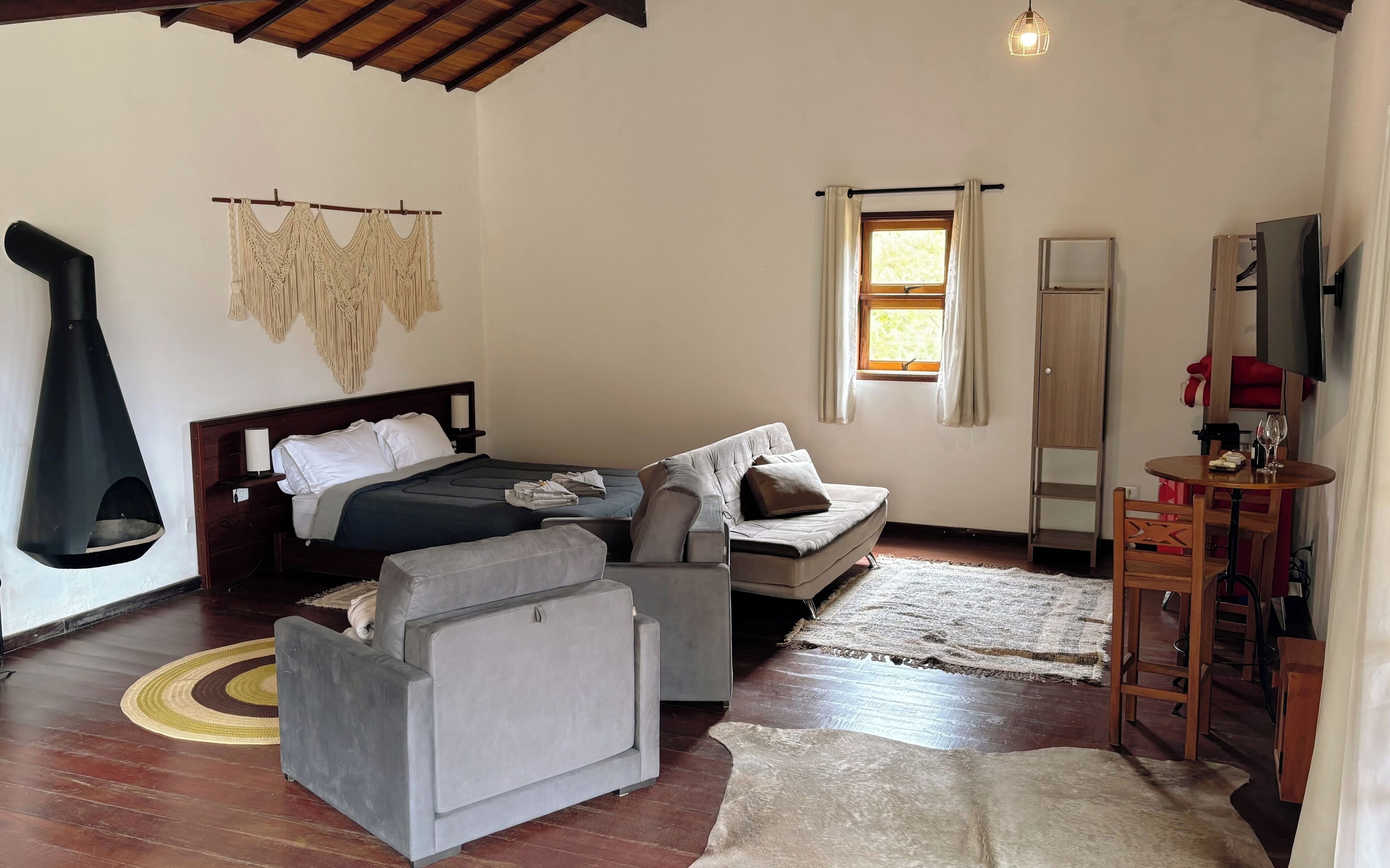 Una habitación acogedora con una cama, dos sofás, un televisor y una chimenea.