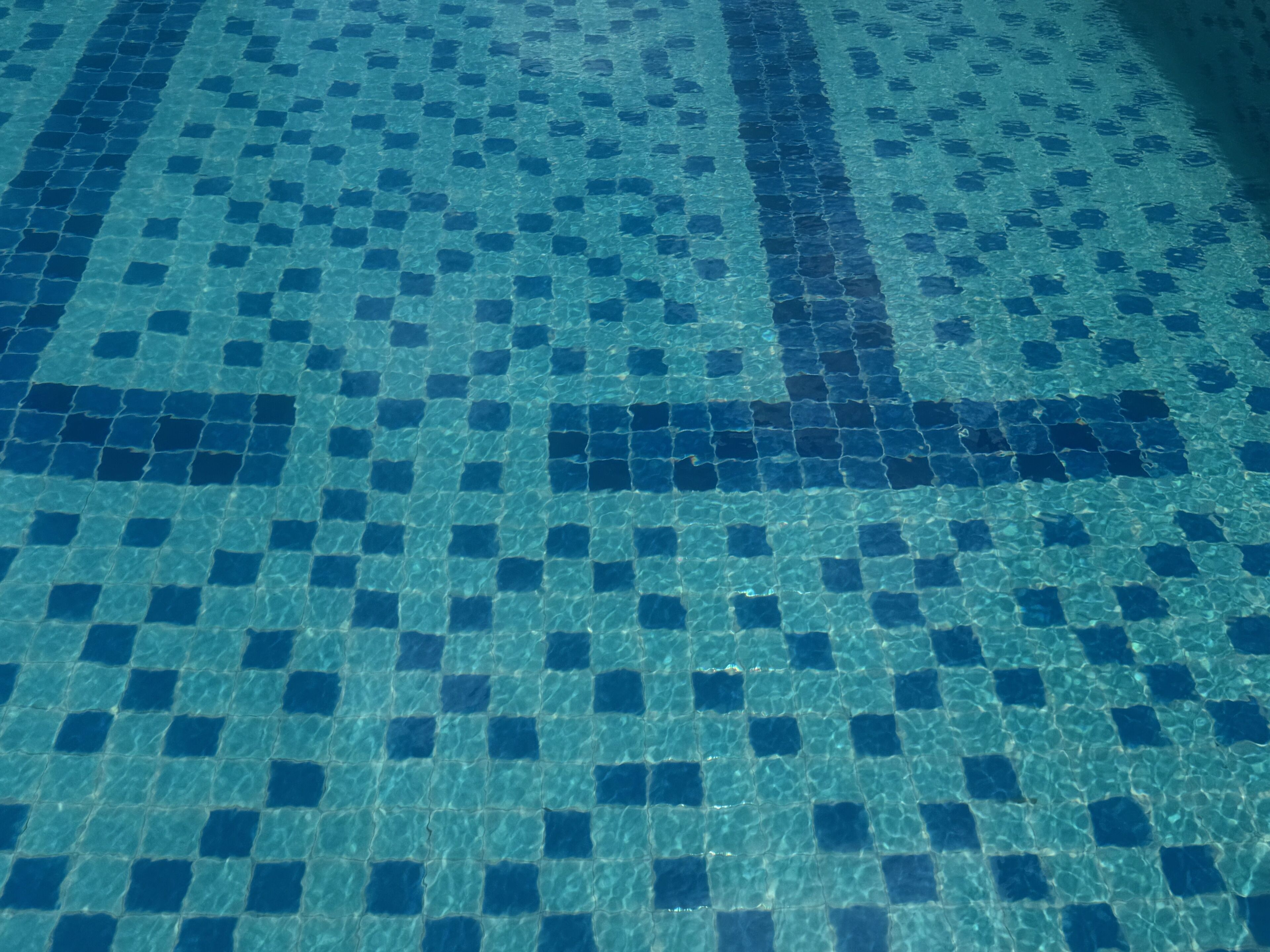 A tiled pool floor with a geometric pattern.