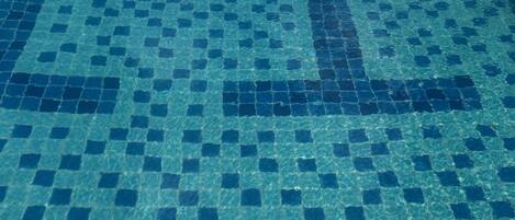A tiled pool floor with a geometric pattern.