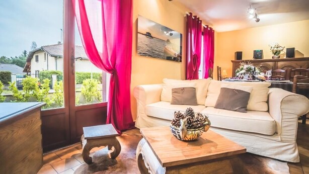 A cozy living room with a sofa, a coffee table with pinecones, and a painting on the wall. - Gîtes chez PAT, a house in the countryside near the beach (Ychoux)