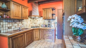 A kitchen with wooden cabinets, a tiled backsplash, a gas stove, a sink, and a decorative orchid plant. - Gîtes chez PAT, a house in the countryside near the beach (Ychoux)