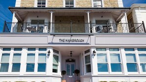 A building with a sign reading "The Hambrook." It features a balcony with metal railings and potted plants. - The Hambrough (Ventnor)