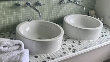 Ein Badezimmer mit zwei weißen Keramikwaschbecken, einem weißen Handtuch und einem Spiegel über den Waschbecken.