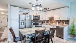 Una cocina moderna con una isla central, electrodomésticos de acero inoxidable y un salpicadero decorativo.