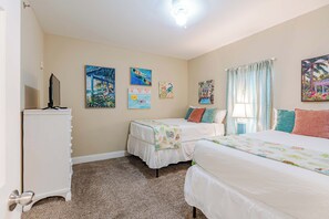 A bedroom with two beds, a dresser, and artwork on the walls.