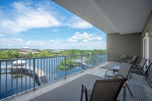A balcony with a view of a river and a dock, furnished with chairs and a table. - Wharftown Retreat at Laketown Wharf 3BR Condo w/ Balcony Views, Pools, Walk to Beach, Sleeps 8 | Daily Entry to Local Activity Options (Panama City Beach)